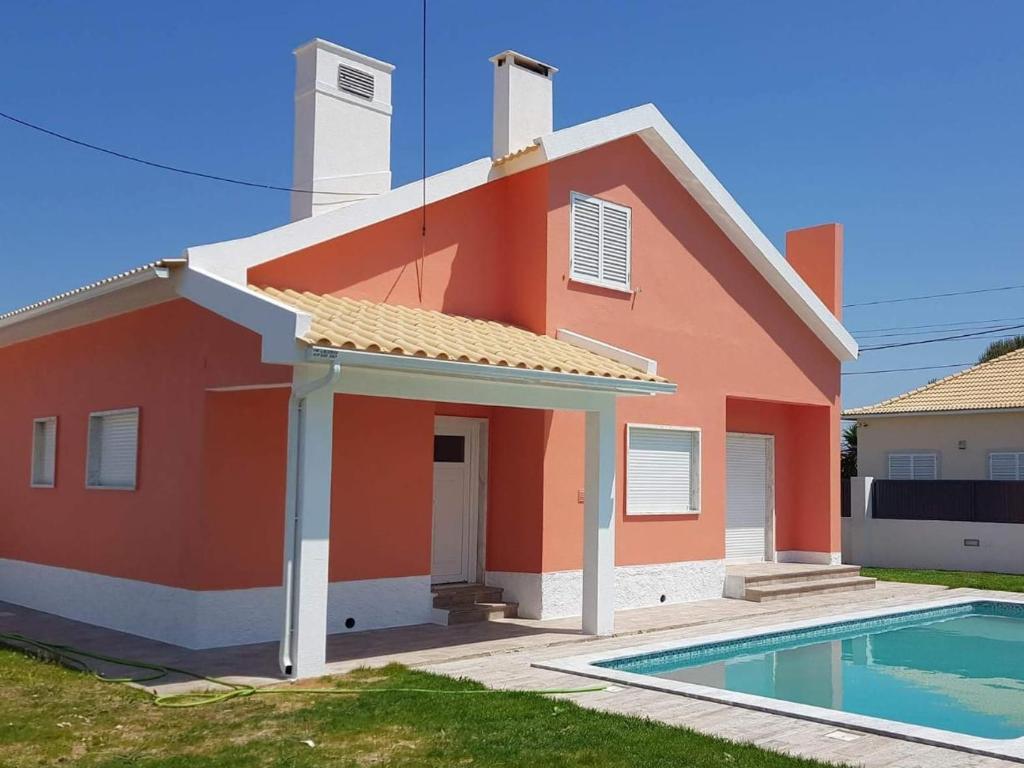 a red house with a swimming pool in front of it at Family Villa Pool & Beach in Caparica