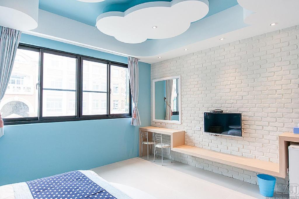a bedroom with blue ceilings and a white brick wall at Yellow Kite Hostel in Tainan