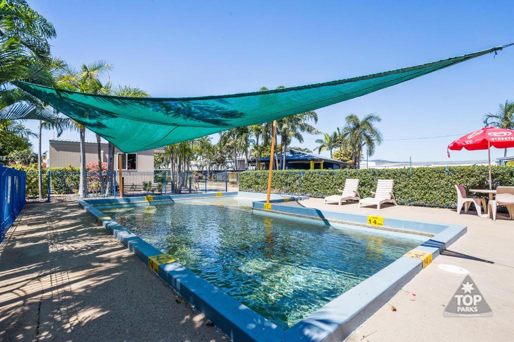 a pool with a blue umbrella on top of it at Coral Coast Tourist Park in Townsville