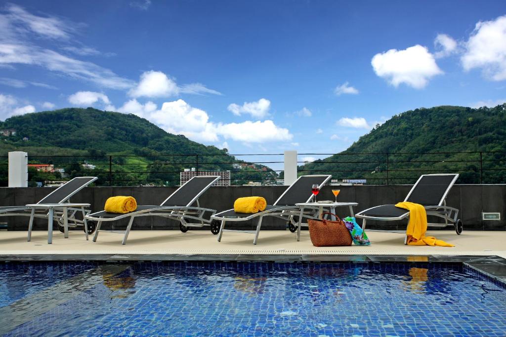 a group of chairs sitting next to a swimming pool at ASHLEE Hub Hotel Patong in Patong Beach