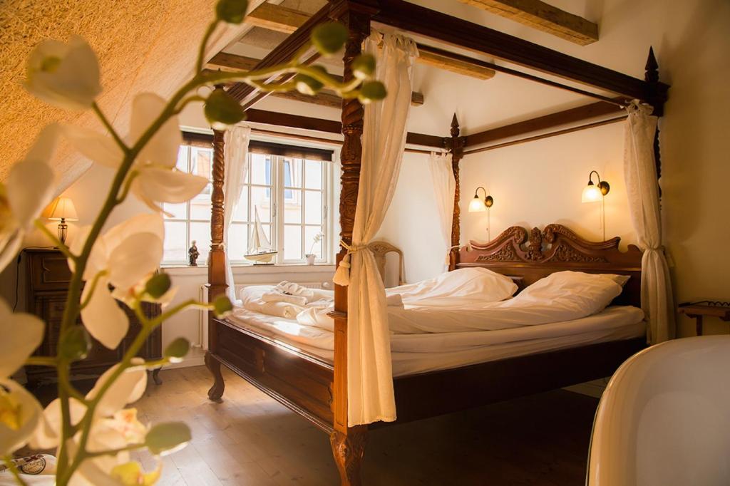 a bedroom with a canopy bed and a window at Boutique Hotel Postgården in Holsted