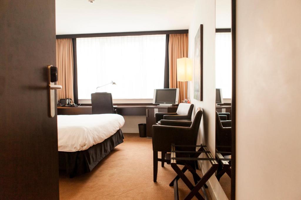 a hotel room with a bed and a desk and a chair at Progress Hotel in Brussels