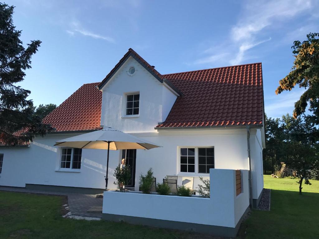 a white house with an umbrella in the yard at Ferienhaus Lilli in Pruchten