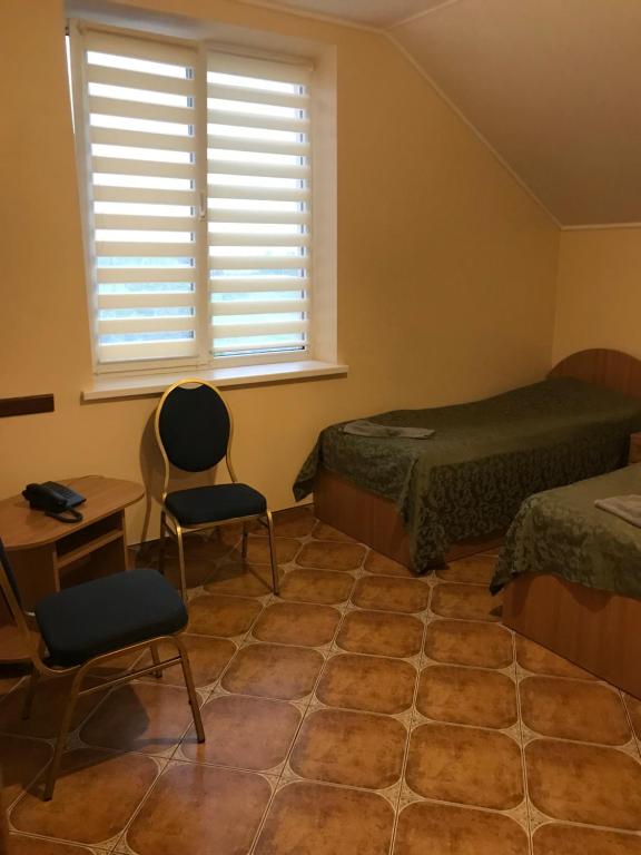 sypialnia z 2 łóżkami, oknem i krzesłem w obiekcie Делікатеси мотель w mieście Rava-Rusʼka