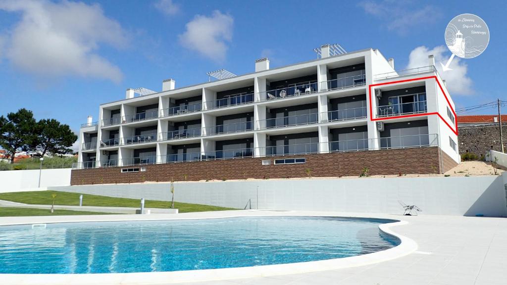 a building with a swimming pool in front of a building at Silver Breezes Apartment in Nazaré