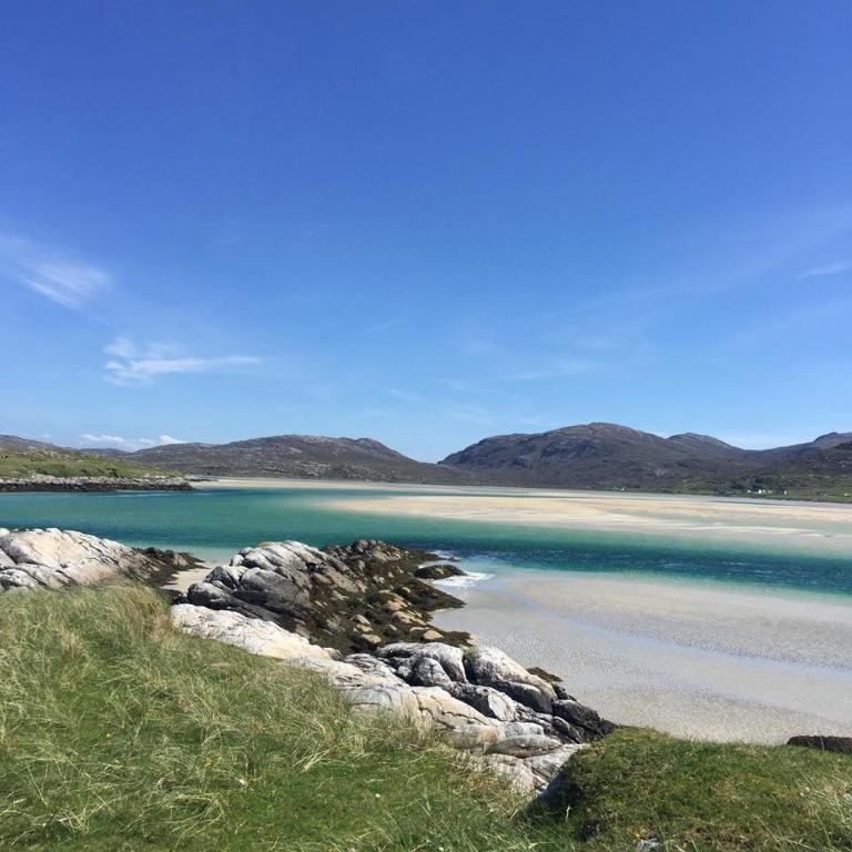 a beach with blue water and mountains in the background at George's House - 1 Leacklee in Manish