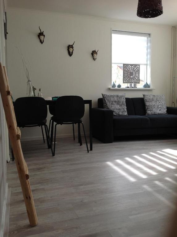 sala de estar con sofá negro y sillas en Me Oissie, en Egmond aan Zee