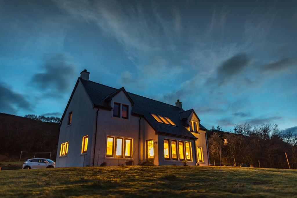 une maison éclairée le soir dans l'établissement Hazeldean, à Colbost