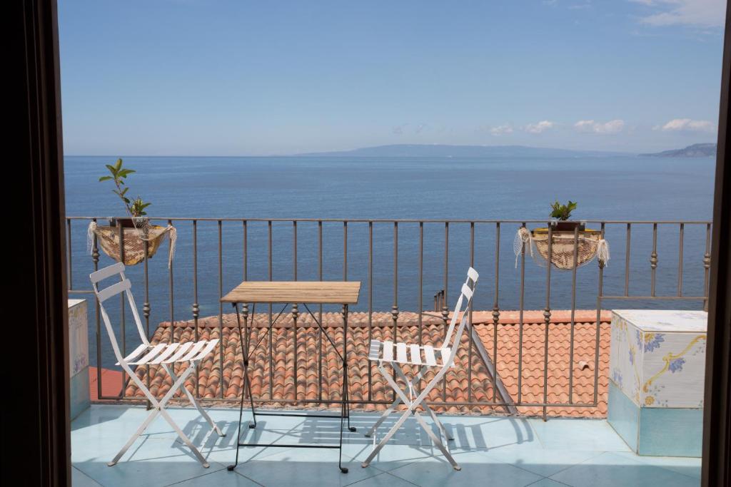 2 Stühle und ein Tisch auf dem Balkon mit Meerblick in der Unterkunft Casa Vela B&B in Scilla