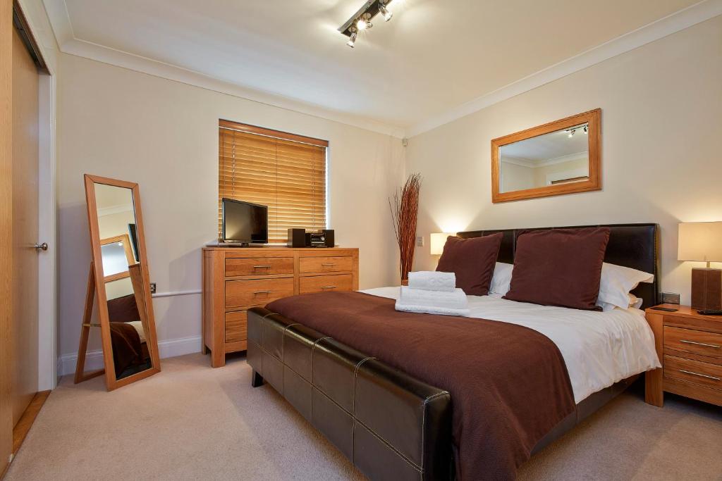 2 bed 2 bath at Jago Crt in Newbury - FREE allocated parking في نيوبري: غرفة نوم بسرير ومرآة وتلفزيون