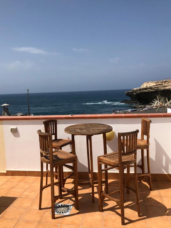 een tafel en stoelen op een balkon met uitzicht op de oceaan bij Vivienda Vacacional Casa Ola in Ajuy