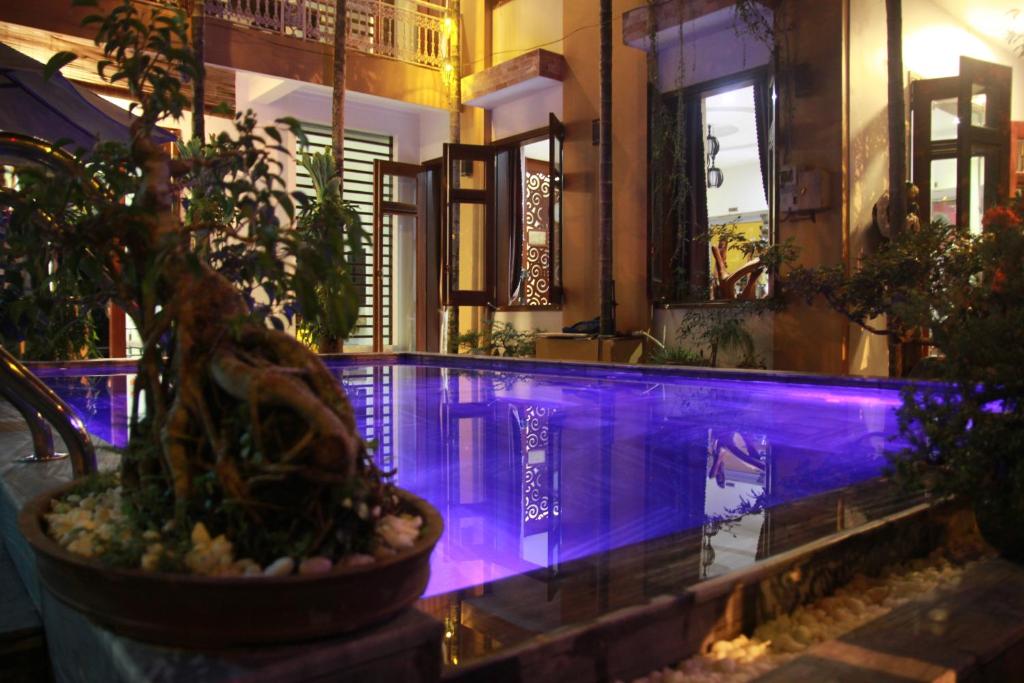 einen Pool mit violetter Beleuchtung in einem Gebäude in der Unterkunft Hoi An Golden Horse Villa in Hoi An
