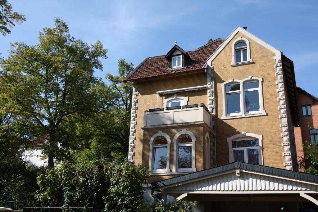 ゴスラーにあるFerienwohnung Bornemannの白い窓と木々が並ぶ茶色レンガ造りの家