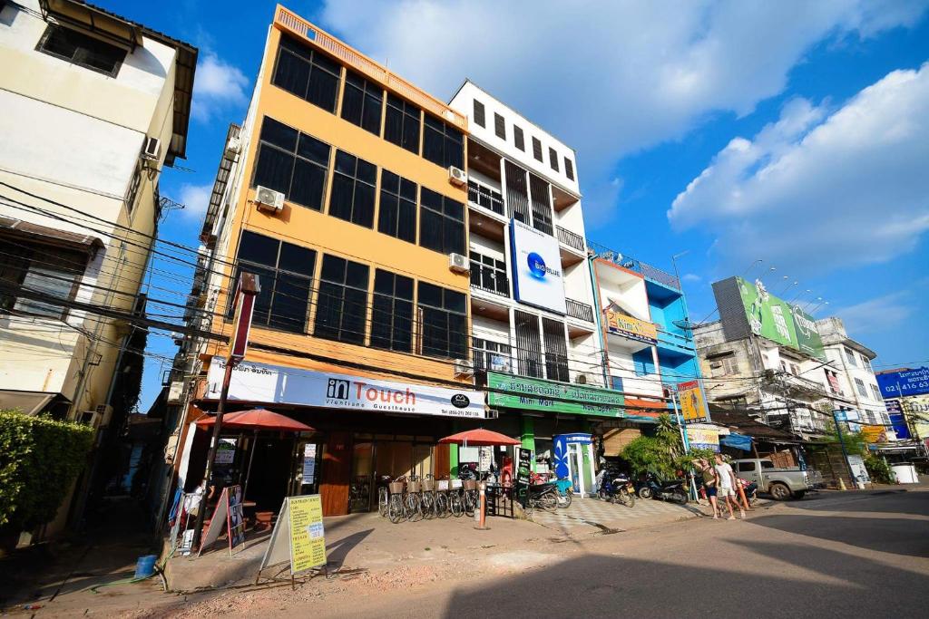 a tall yellow building on the side of a street at Intouch Guest House in Vientiane