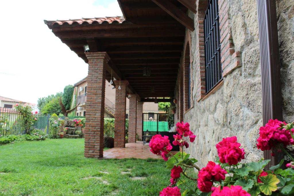 ein Backsteinhaus mit roten Blumen im Hof in der Unterkunft Casa Rural Aguas del Venero in Losar de la Vera