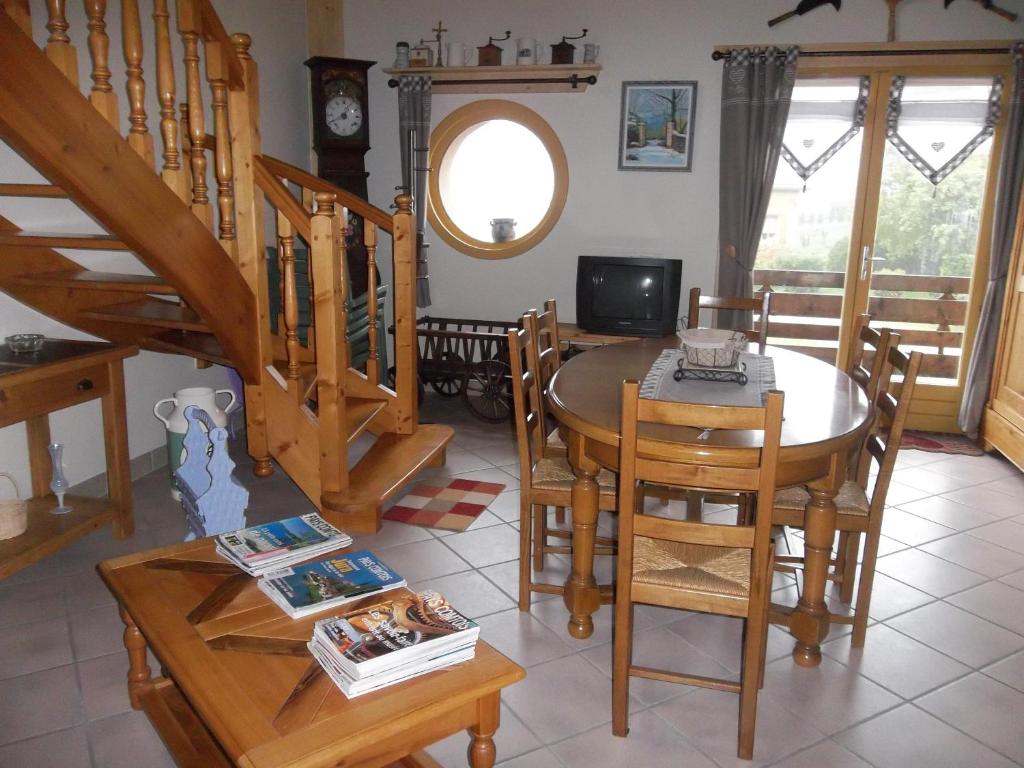 een eetkamer met een tafel en stoelen en een televisie bij Le Chant du Coq in Bief-des-Maisons