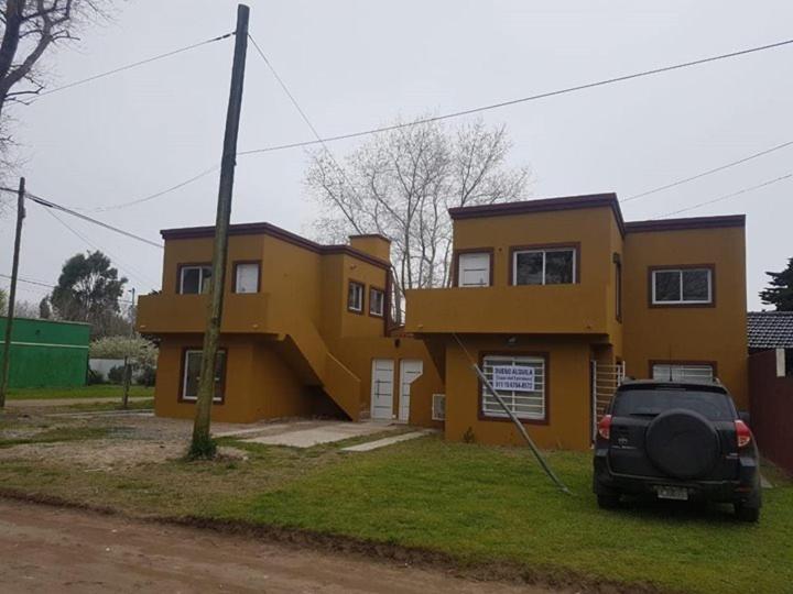 a truck parked in front of a yellow house at Departamento Alquiler Costa Azul para 5 personas in Costa Azul