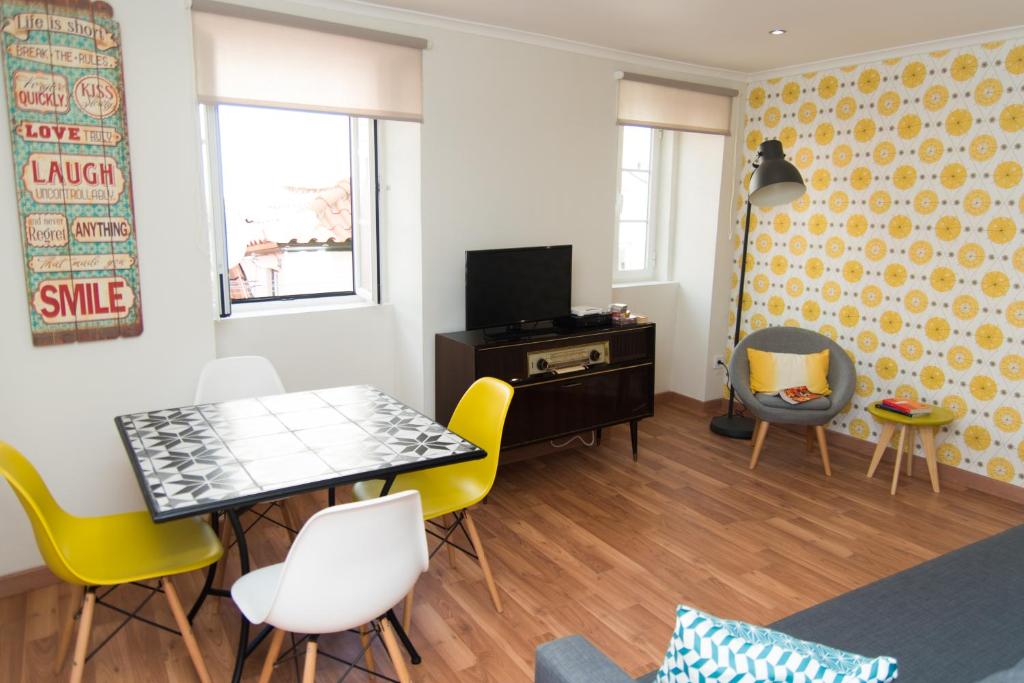 uma sala de estar com uma mesa e cadeiras amarelas em Casa da Espera em Lisboa