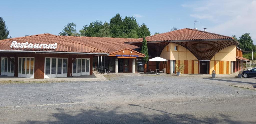 um edifício com um parque de estacionamento em frente em Hôtel Eco Logis em Séméac