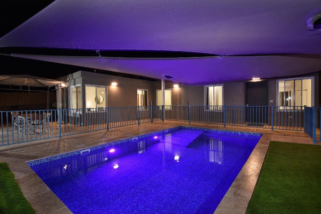 una piscina con luces moradas en un edificio en Shmulik's Resort, en Had Nes
