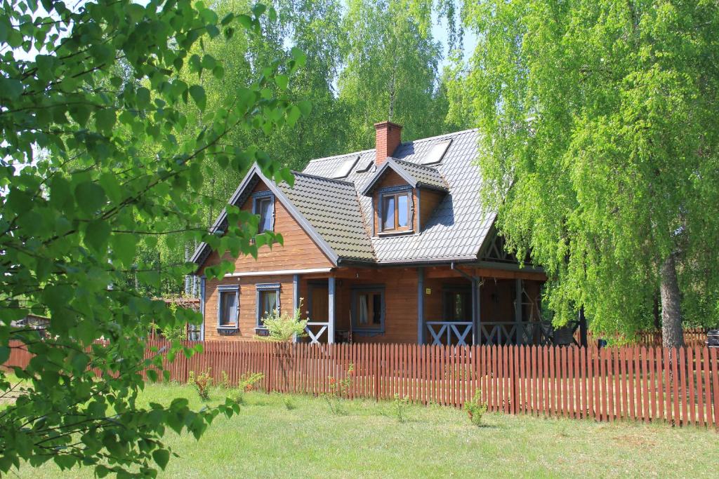 uma casa de madeira com uma cerca em frente em Żubrowe Sioło - dom na wyłączność em Białowieża
