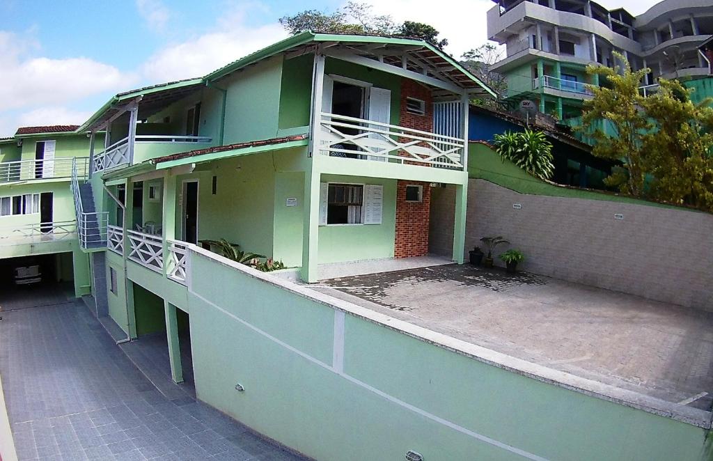 a green house with a balcony and a building at Pousada Águas Formosas in Ubatuba