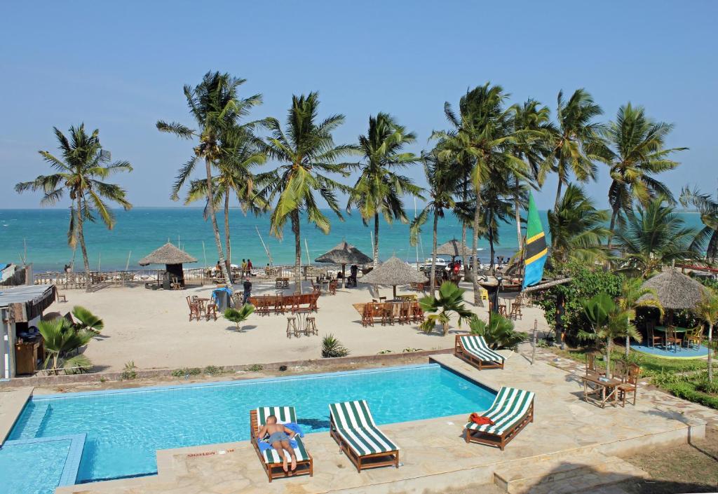 a resort with a pool and a beach with palm trees at Villa Dahl Beach Resort in Dar es Salaam