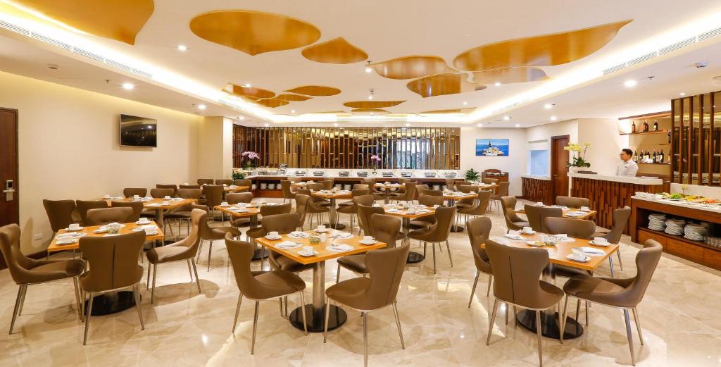 ホーチミン・シティにあるOrchids Saigon Hotelのテーブルと椅子とバーのあるレストラン
