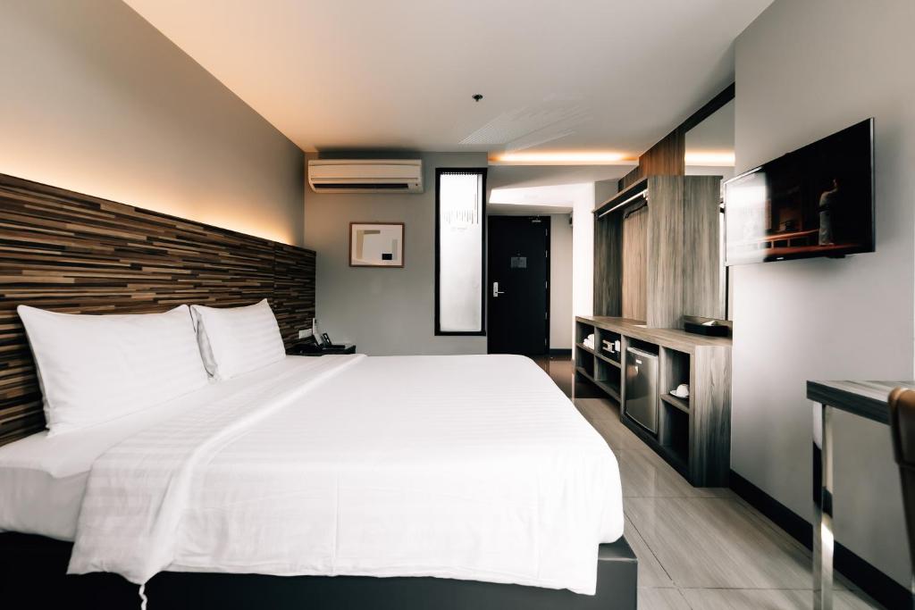a bedroom with a large white bed and a television at Spenza Hotel in Bangkok