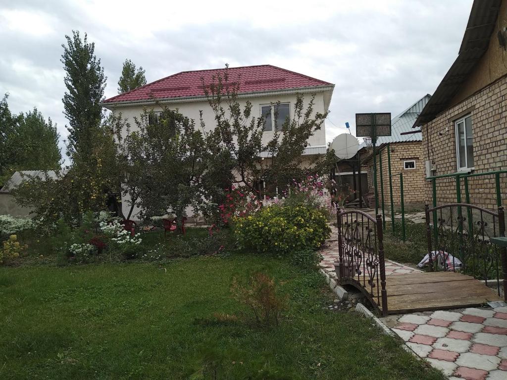 a house with a fence and a yard with flowers at Talants Guest House in Bishkek