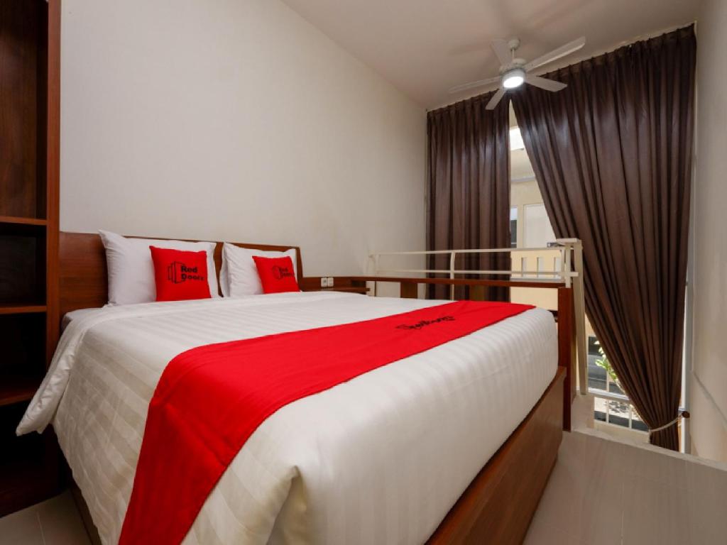 a bedroom with a large bed with a red blanket at RedDoorz Plus near Paragon Mall Semarang in Semarang