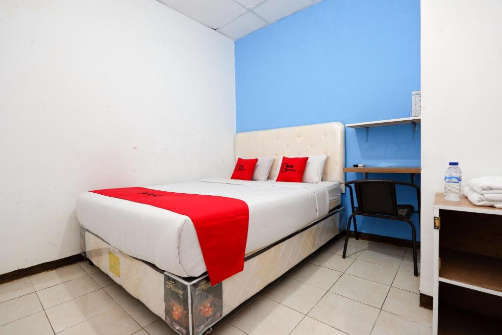a bedroom with a bed with a red blanket on it at RedDoorz Near Kota Lama Semarang in Semarang