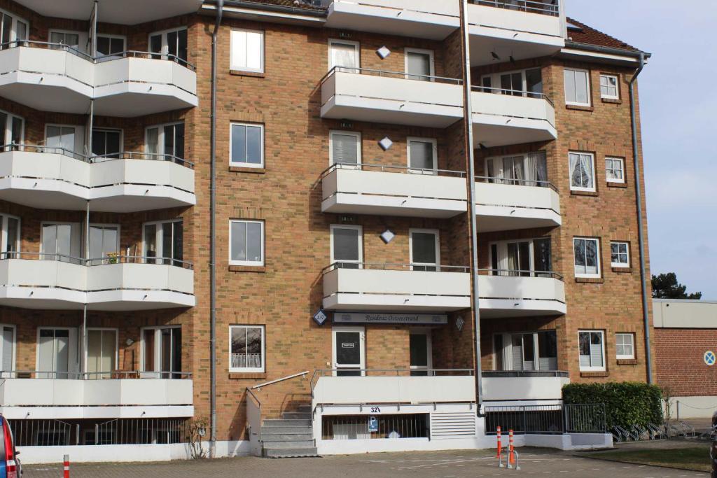 un gran edificio de ladrillo con balcones blancos. en Residenz Ostseestrand Nr_ 11, en Scharbeutz