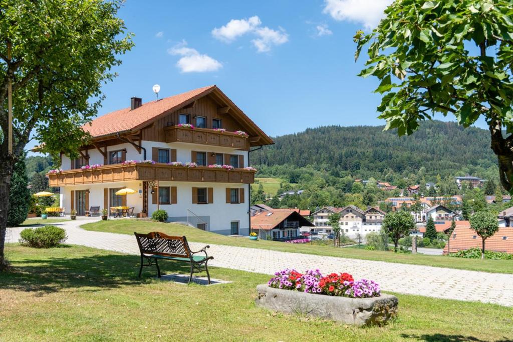 eine Bank vor einem Haus mit Blumen in der Unterkunft Ferienwohnungen Haus Elisabeth in Bodenmais