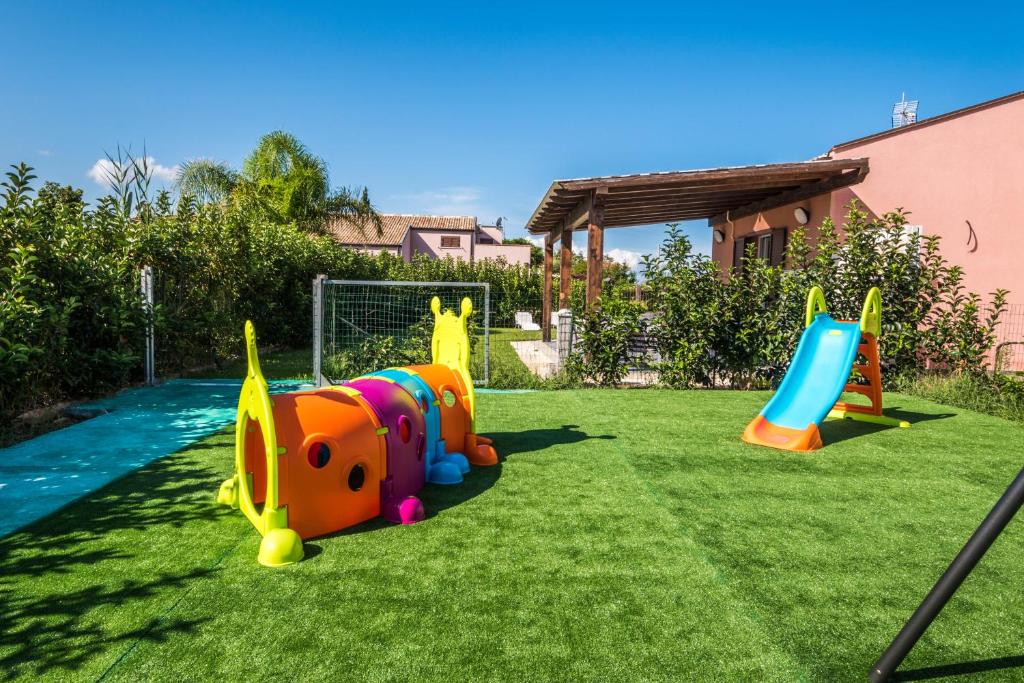 a playground in a yard with some toys on the grass at Villa Ricky, a pochi passi dal mare in Lascari