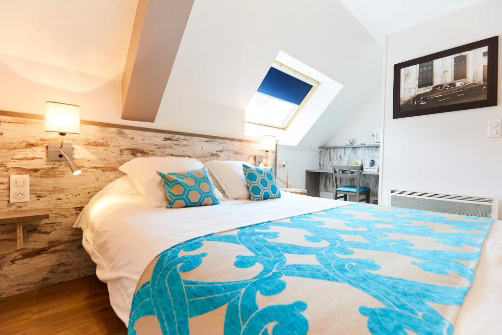 a bedroom with a large bed with blue and white pillows at Auberge Du Cheval Blanc in Baud