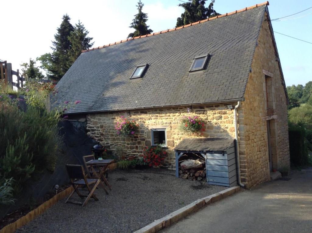 un pequeño edificio de piedra con chimenea frente a él en The Grange en Les Portes du Coglais