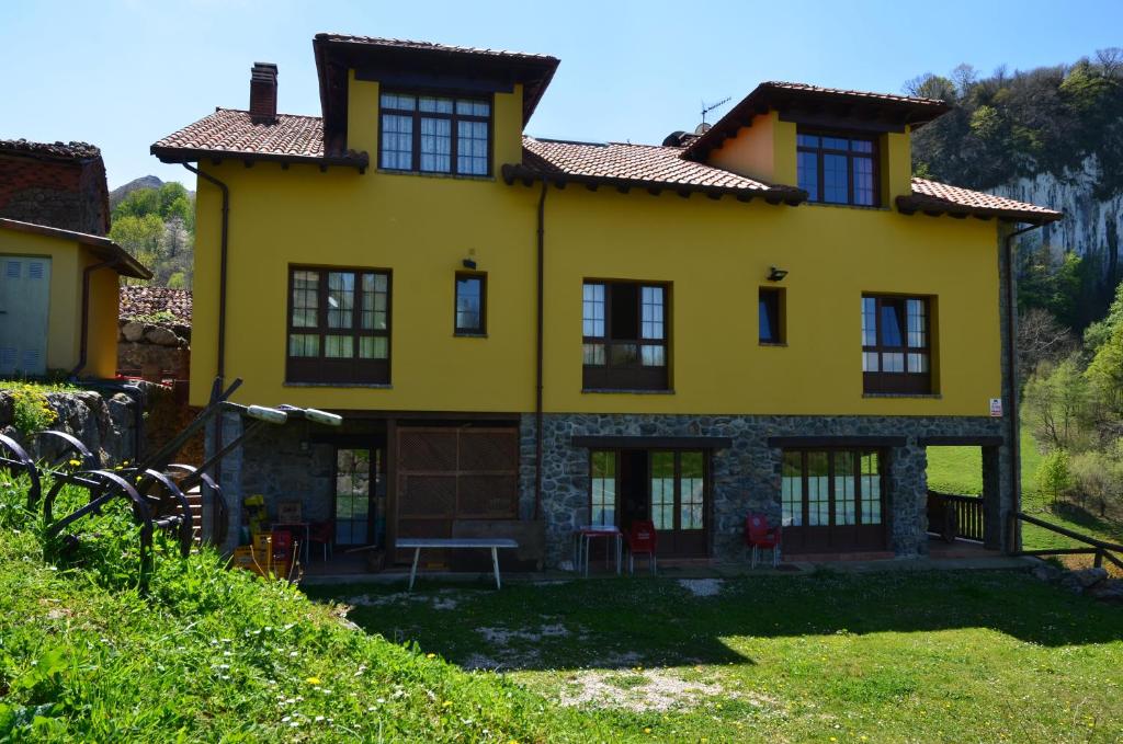 a yellow house with black windows on a hill at El Quesar de Gamoneo in Gamonedo de Cangas