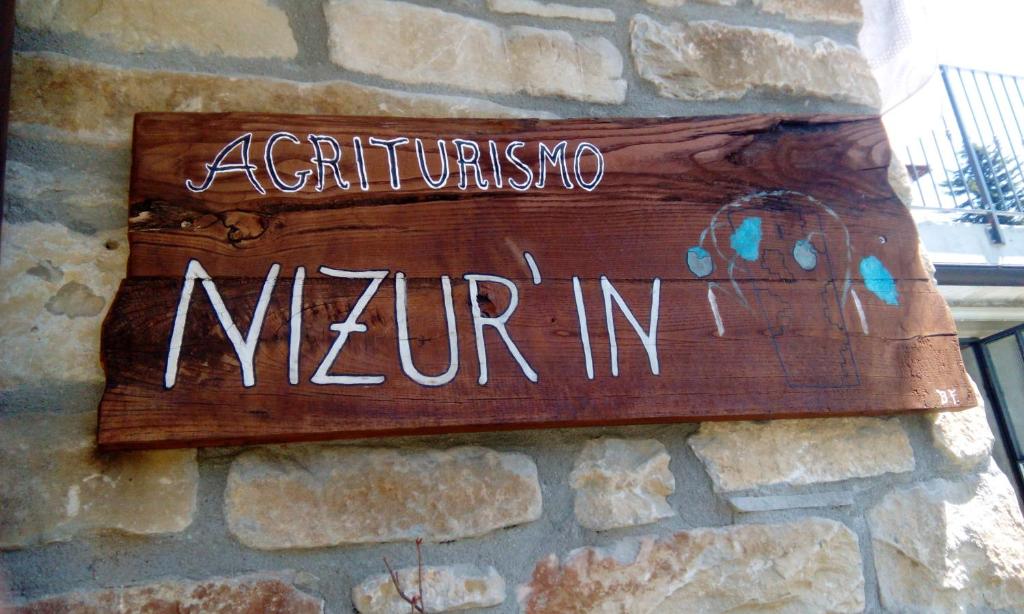 un cartello sul lato di un muro di pietra di AGRITURISMO NIZUR'IN a Roccaverano