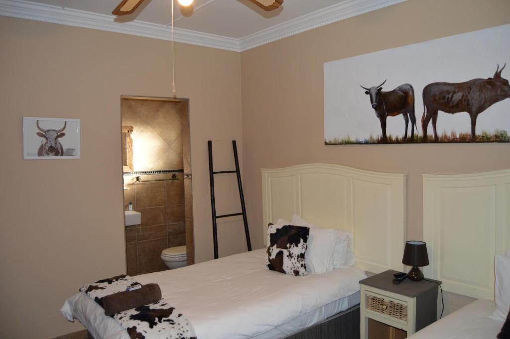 a bedroom with two beds and a painting of animals on the wall at Esmarline Lodge in Brits