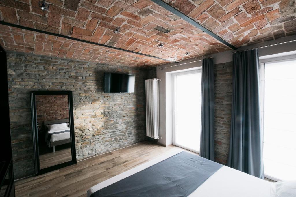 een slaapkamer met bakstenen muren, een bed en een spiegel bij Villa Barbero Alba in Mango
