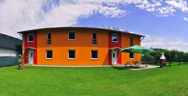a large orange house with a green grassy yard at Privat Monika in Liptovský Mikuláš