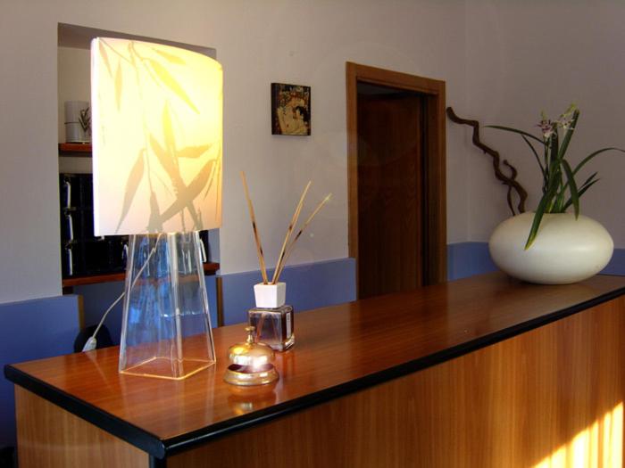 a desk with a lamp and a vase on it at Hotel Blu in Rieti