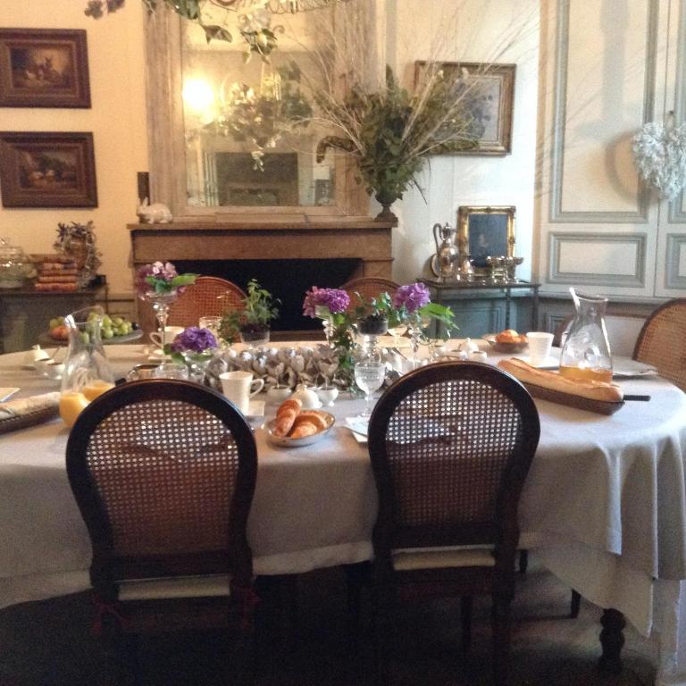 a dining room table with a white table cloth and two chairs at Le Clôs Ste Anne in Eu
