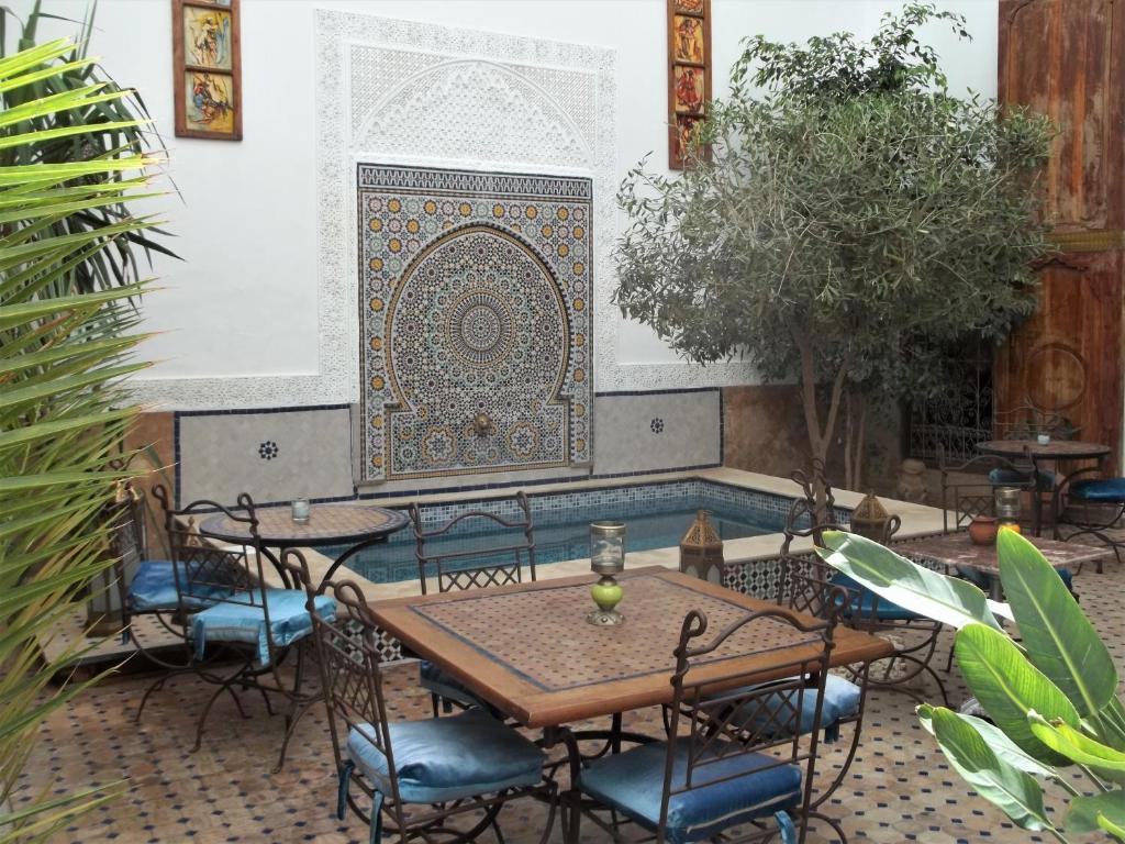 a patio with a table and chairs and a wall at Riad Attarine in Fez