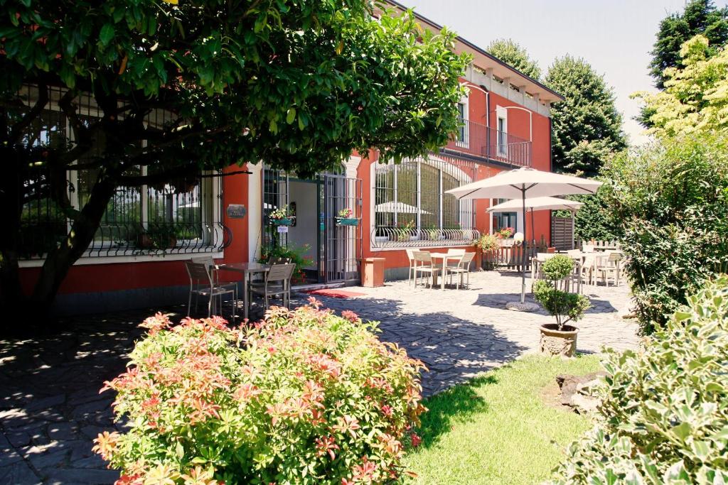 a garden with tables and chairs and a building at Hotel De La Ville in Bereguardo