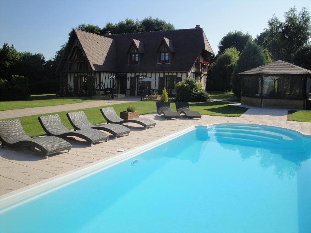 a swimming pool with lounge chairs and a house at Gîtes Les Colombages in Fatouville-Grestain