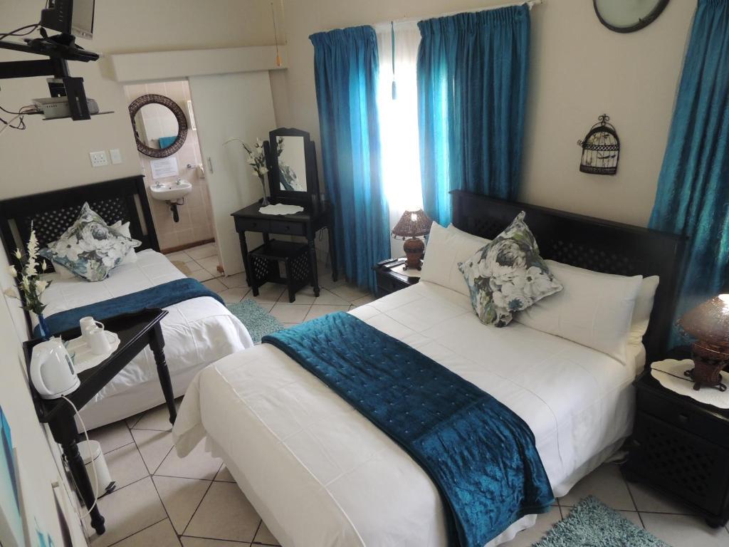 a bedroom with two beds and blue curtains at Rita's Guesthouse CC in Vryheid