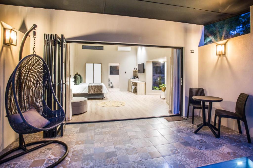 a living room with a chair and a bedroom at Hlangana Lodge in Oudtshoorn
