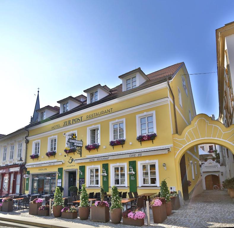 ein gelbes Gebäude mit Topfpflanzen davor in der Unterkunft Hotel Restaurant zur Post in Melk